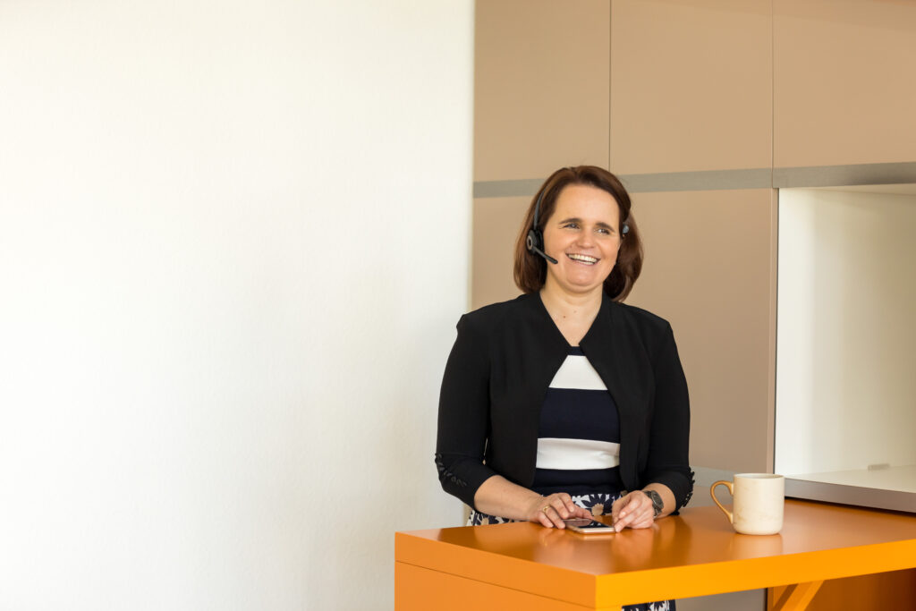 Astrid Weidner telefoniert mit Handy und Headset.